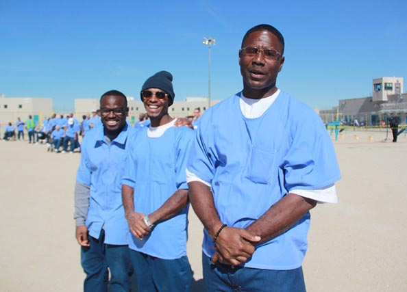 Three incarcerated men standing outside smiling