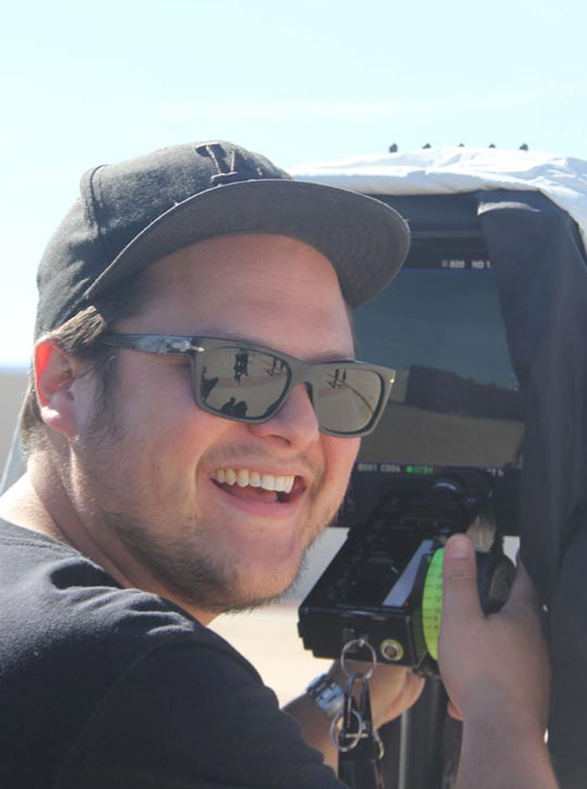 Videocamera man wearing sunglasses on the set of Step Inside The Circle smiling