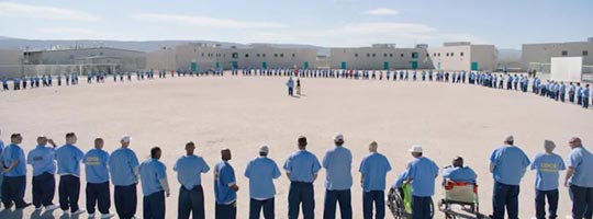 Woman with microphone standing in middle of circle of 235 incarcerated men