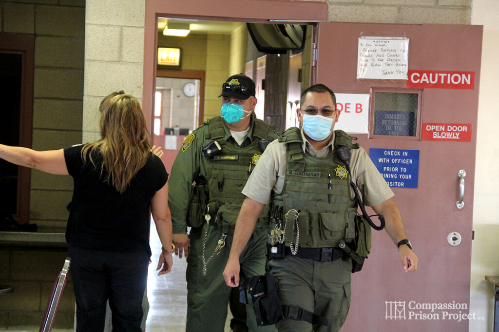 Correctional Officers walking in a room wearing masks