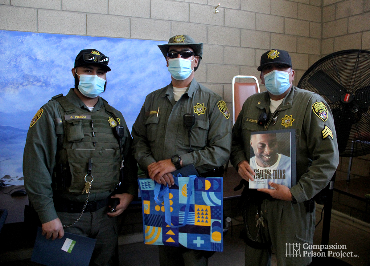 3 correctional officers holding Trauma Talks workbook and bag