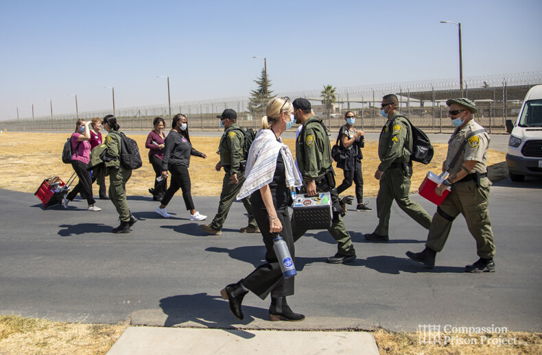 Woman and group of volunteers walking passed a group of correctional officers